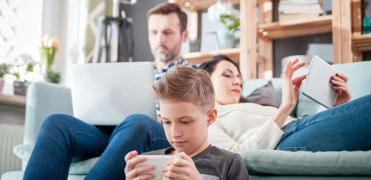 Family at home on the sofa all using devices